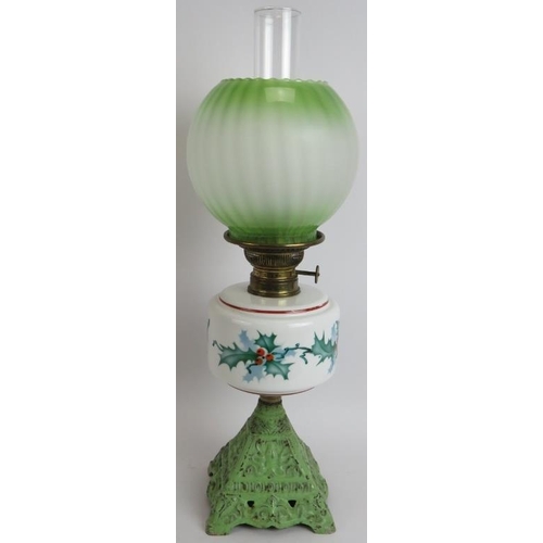 158 - An early 20th century continental oil lamp with cast iron base, hand decorated Holly pattern reservo... 