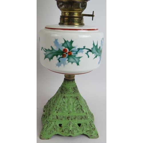 158 - An early 20th century continental oil lamp with cast iron base, hand decorated Holly pattern reservo... 