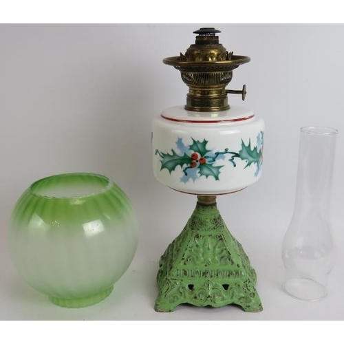 158 - An early 20th century continental oil lamp with cast iron base, hand decorated Holly pattern reservo... 