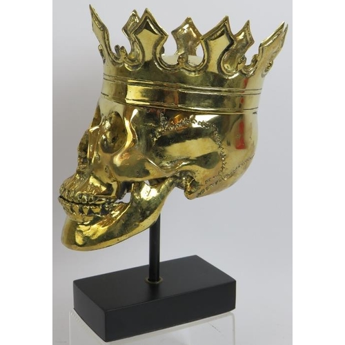 16 - A contemporary polished bronze model of a human skull wearing a crown mounted on a bespoke plinth. O... 