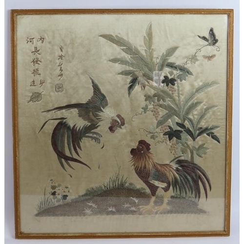 182 - An antique Chinese silk work panel depicting a pair of fighting cockerels with Chinese characters an... 