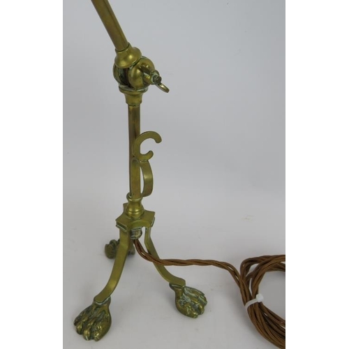 285 - A brass Arts & Crafts desk lamp with adjustable arm, standing on lion paw feet and with a green Vase... 