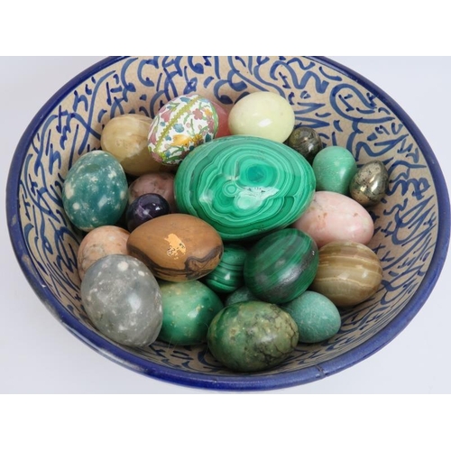 62 - A blue and white Islamic pottery bowl containing a collection mainly semi precious stone eggs includ... 