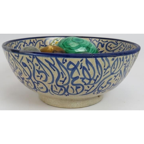 62 - A blue and white Islamic pottery bowl containing a collection mainly semi precious stone eggs includ... 