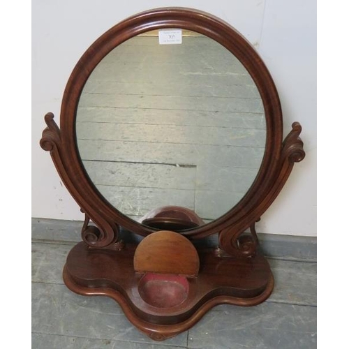 705 - A Victorian mahogany oval swing vanity mirror, with scrolled and pierced uprights, on a shaped plint... 