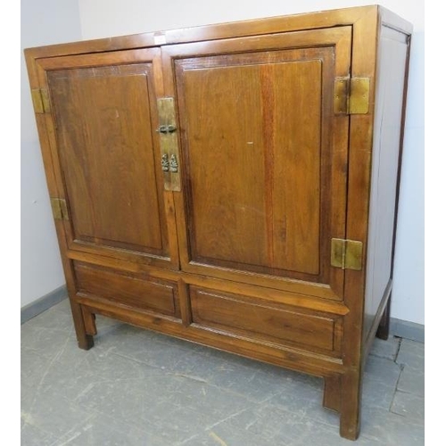 712 - A vintage tropical hardwood Chinese wedding cabinet with brass fittings, the double doors opening on... 