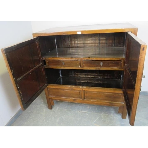 712 - A vintage tropical hardwood Chinese wedding cabinet with brass fittings, the double doors opening on... 