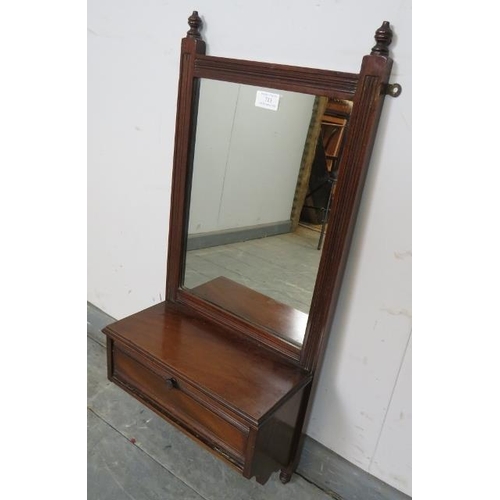 713 - An Edwardian mahogany wall mirror with reeded detail and turned finials, above a box base with fall ... 