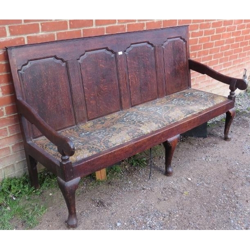 723 - An 18th century oak settle, the backrest with fielded panels, joined with open-sided armrests, on ca... 