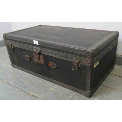 725 - An antique travelling trunk by Malles Goyard of Paris, bound with leather strapwork and brass studs,... 