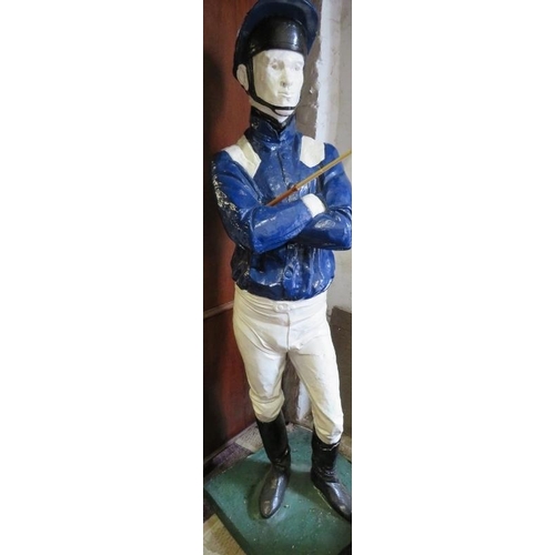 738 - A life-size painted plaster figure of a jockey in racing colours, with riding crop, on a plinth base... 