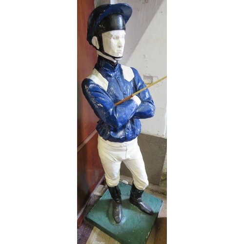 738 - A life-size painted plaster figure of a jockey in racing colours, with riding crop, on a plinth base... 