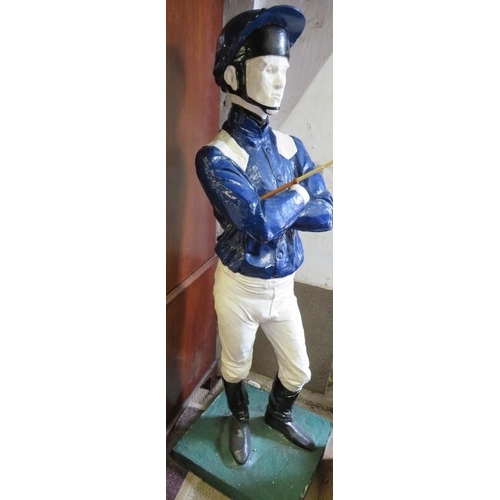 738 - A life-size painted plaster figure of a jockey in racing colours, with riding crop, on a plinth base... 