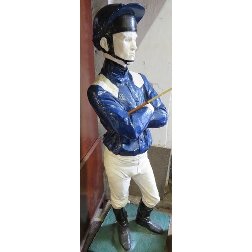 738 - A life-size painted plaster figure of a jockey in racing colours, with riding crop, on a plinth base... 