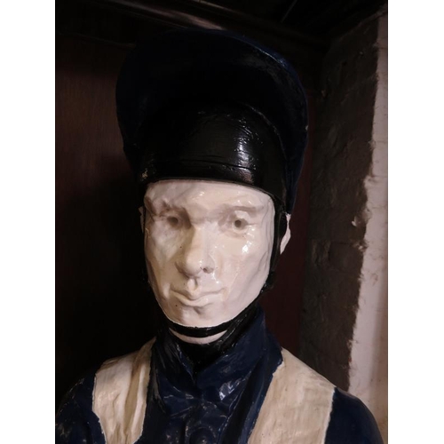 738 - A life-size painted plaster figure of a jockey in racing colours, with riding crop, on a plinth base... 