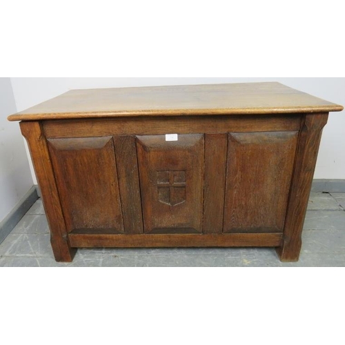 741 - An Arts & Crafts oak coffer with fielded panels to all four sides and a relief carved shield to cent... 