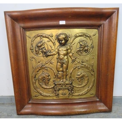 750 - A Rococo embossed gilt brass panel depicting a cherub holding compasses and quill, mounted in an oak... 