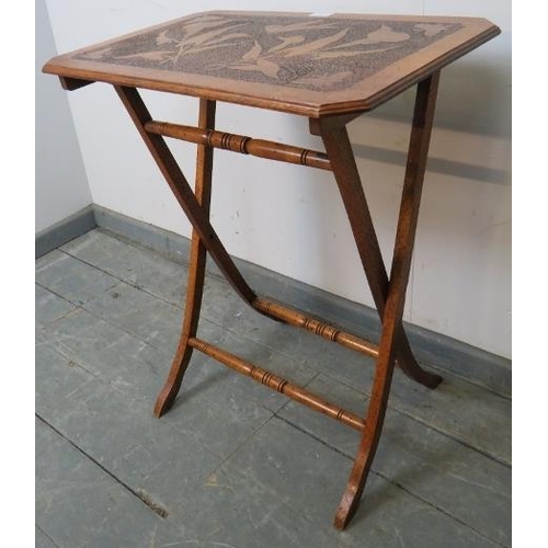 757 - An Arts & Crafts walnut folding side table with pokerwork top depicting flora and fauna, on X frame ... 