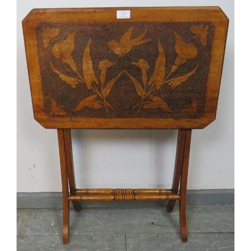 757 - An Arts & Crafts walnut folding side table with pokerwork top depicting flora and fauna, on X frame ... 