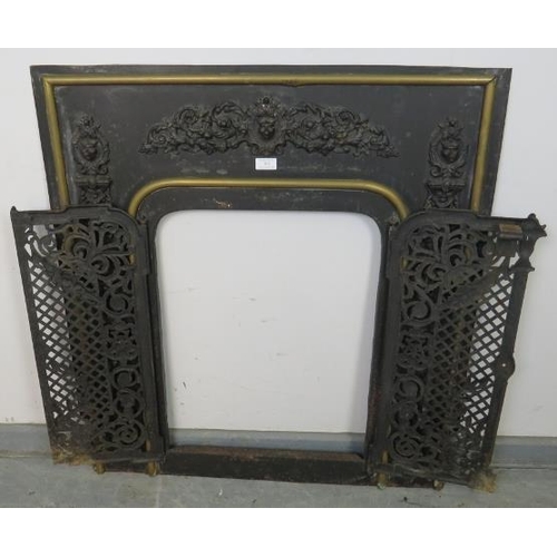 762 - An antique cast iron and brass fireplace insert, the applied decoration depicting scrolling acanthus... 