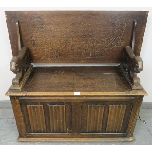 771 - An antique oak monk’s bench, with metamorphic backrest and carved arms in the form of lions, over a ... 