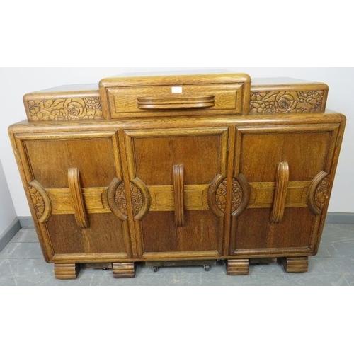 773 - An Art Deco medium oak sideboard, with central drawer flanked by lidded compartments, above three cu... 