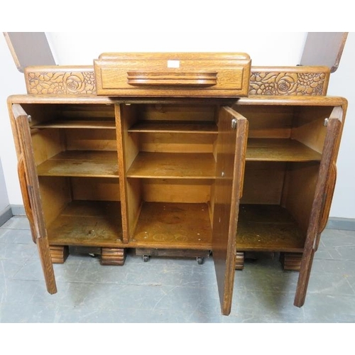 773 - An Art Deco medium oak sideboard, with central drawer flanked by lidded compartments, above three cu... 