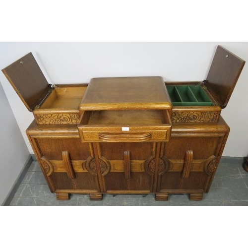 773 - An Art Deco medium oak sideboard, with central drawer flanked by lidded compartments, above three cu... 