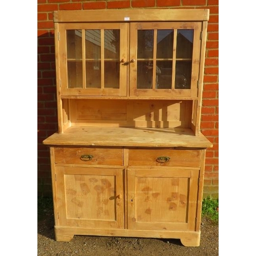 776 - An antique stripped pine kitchen dresser, the glazed doors opening onto one loose shelf, over a side... 