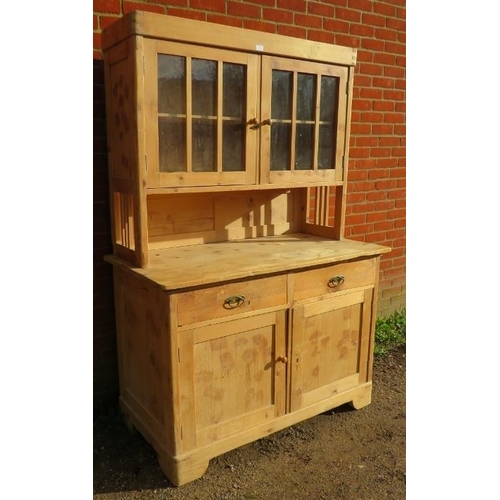 776 - An antique stripped pine kitchen dresser, the glazed doors opening onto one loose shelf, over a side... 