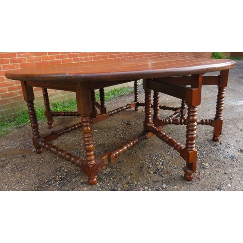 779 - A large heavy oak gate-leg table with cast iron studs, on turned and block supports united by turned... 