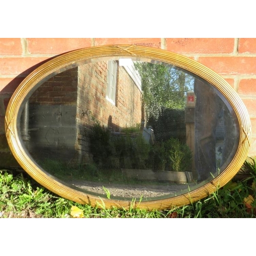 784 - A vintage oval bevelled wall mirror with beaded edging, in a gilt gesso frame. With fixings for land... 