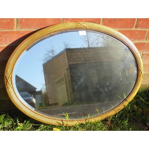 784 - A vintage oval bevelled wall mirror with beaded edging, in a gilt gesso frame. With fixings for land... 