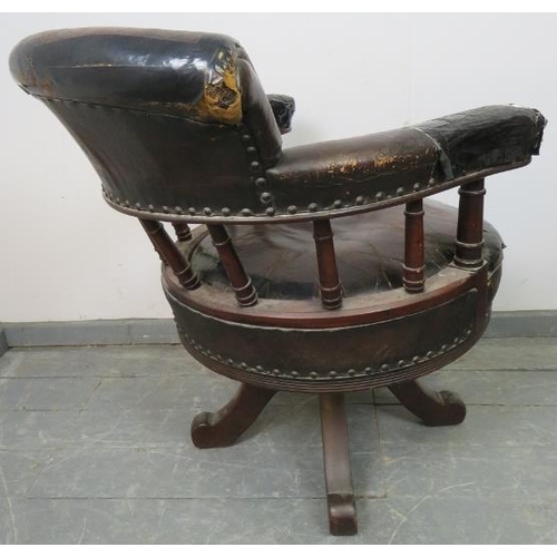 793 - An Edwardian mahogany captain’s swivel desk chair, upholstered in burgundy leather with brass studs,... 