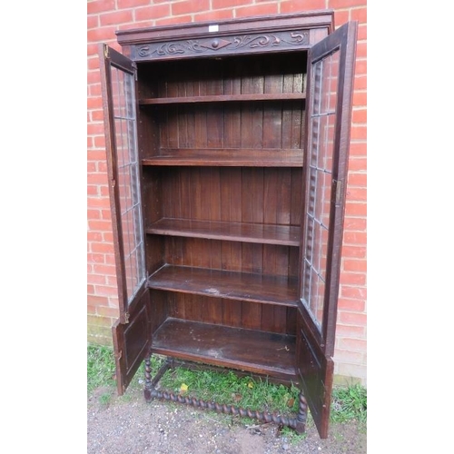 818 - A tall 1920s Jacobean Revival oak bookcase featuring barley twist uprights, the glazed doors with le... 