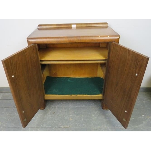 820 - An Art Deco walnut crossbanded sideboard featuring stepped sides, housing two loose shelves, on curv... 