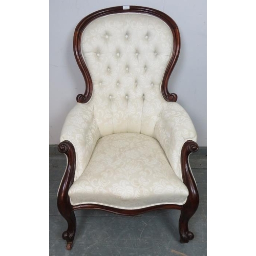 829 - A Victorian mahogany spoon back show-wood armchair with scrolled arms, reupholstered in cream button... 