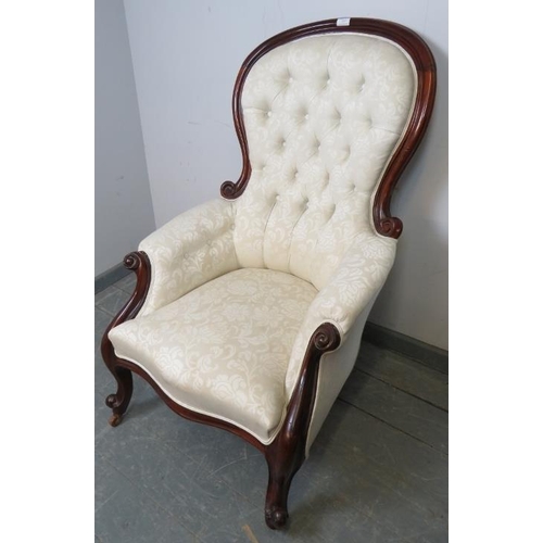 829 - A Victorian mahogany spoon back show-wood armchair with scrolled arms, reupholstered in cream button... 