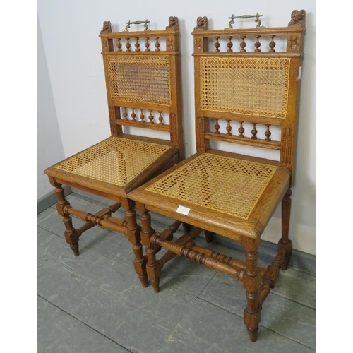 850 - A pair of Edwardian medium oak hall chairs featuring carved lion finials and turned spindles, with b... 