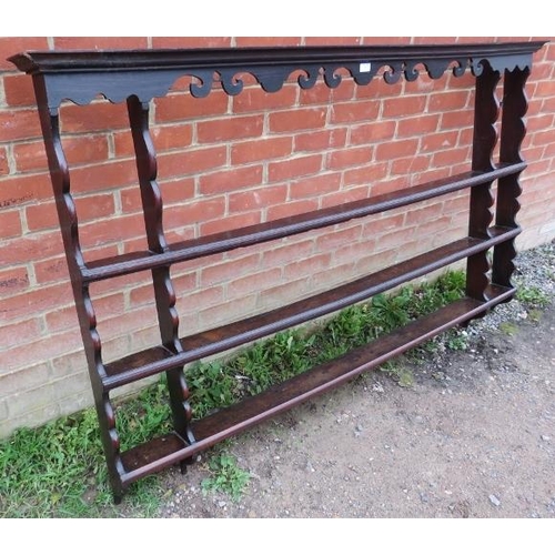 876 - An 18th century oak wall hanging plate rack of three shelves, with shaped cornice and uprights. 
Con... 