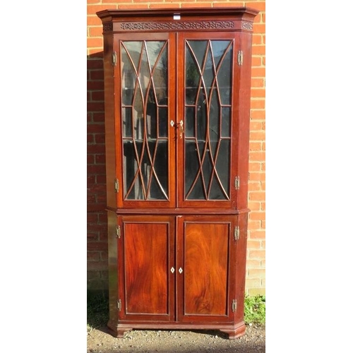 880 - A Georgian flame mahogany tall corner cupboard, with blind fret frieze above astral glazed doors ope... 