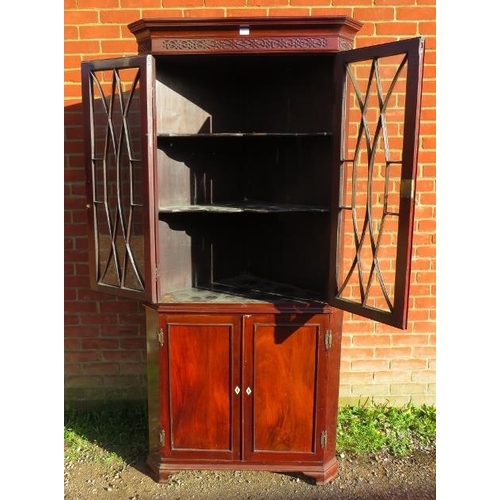 880 - A Georgian flame mahogany tall corner cupboard, with blind fret frieze above astral glazed doors ope... 