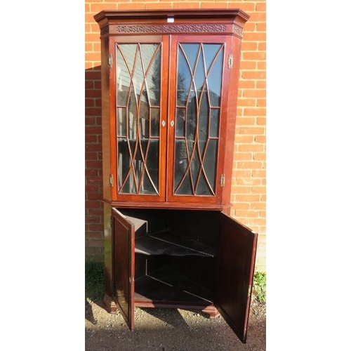 880 - A Georgian flame mahogany tall corner cupboard, with blind fret frieze above astral glazed doors ope... 