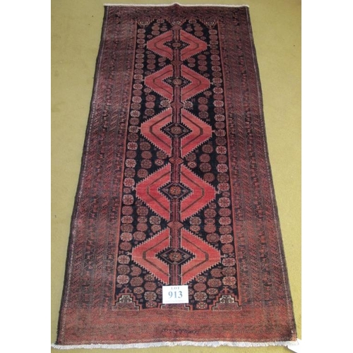 913 - North East Persian Meshed Belouch rug. Central repeat pattern on black ground with a wide slightly f... 