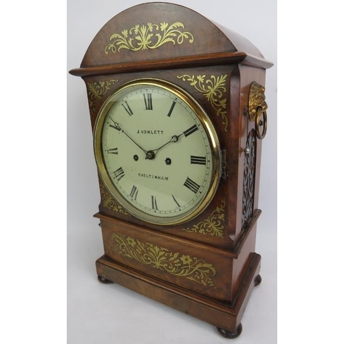 124 - A Regency period brass inlaid mahogany cased mantle clock by J. Howlett of Cheltenham, flanked by br... 