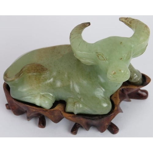 208 - A Chinese carved celadon Jade recumbent water Buffalo, Ming style but likely Qing, resting on a besp... 