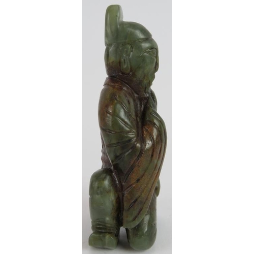 215 - A Chinese carved dark spinach Jade crouching Sage, holding his beard in a ponderous pose, with russe... 