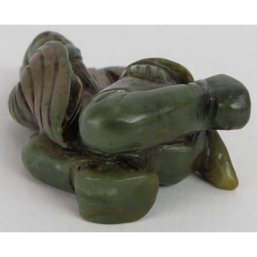 215 - A Chinese carved dark spinach Jade crouching Sage, holding his beard in a ponderous pose, with russe... 