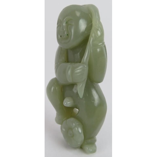 220 - A Chinese carved celadon Jade figure of a boy holding a branch above his head and standing on a flow... 