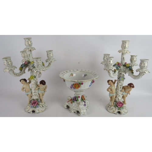 283 - A pair of hand decorated Dresden porcelain four branch candelabra with Putti decoration and a simila... 